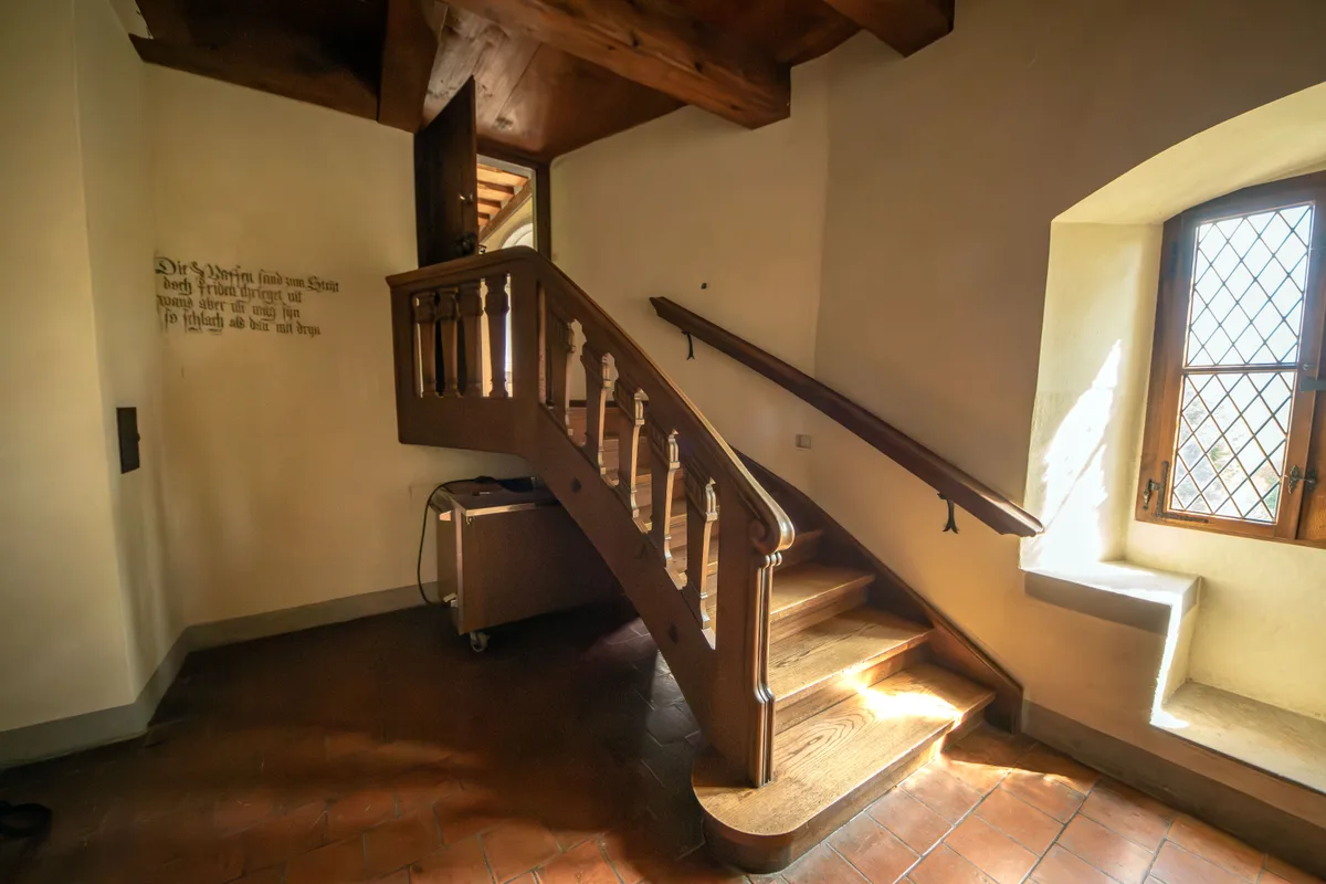 Eine Treppe führt neben einem Wandspruch vorbei.